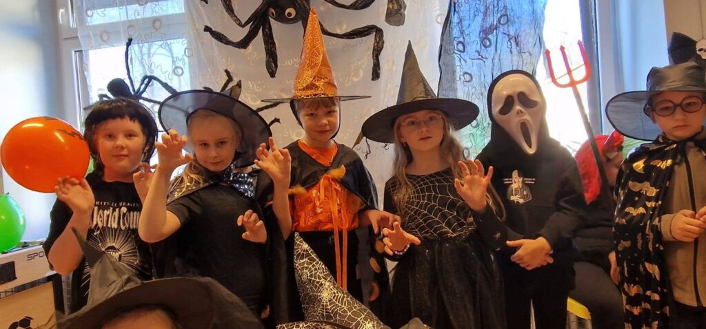 „Uczniowie w halloweenowych przebraniach podczas Upiornego Balu Halloweenowego w świetlicy szkolnej.”