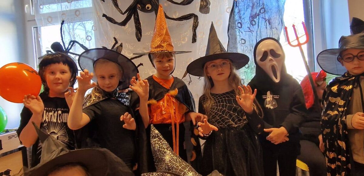 „Uczniowie w halloweenowych przebraniach podczas Upiornego Balu Halloweenowego w świetlicy szkolnej.”