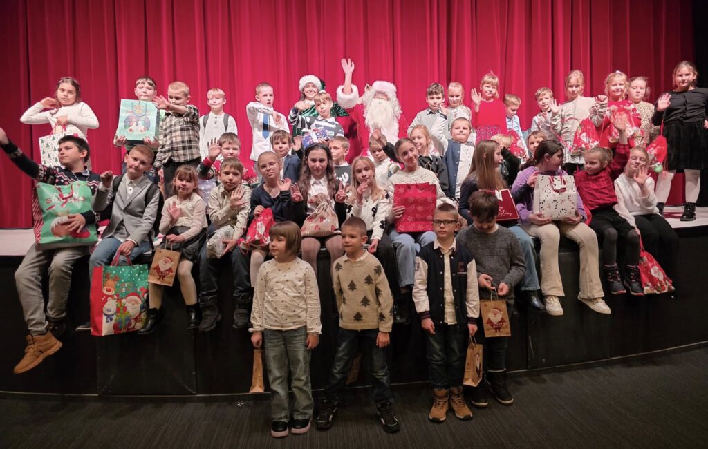 Zdjęcie przedstawia uczniów klas od 1-3, siedzących na scenie w teatrze w towarzystwie św. Mikołaja