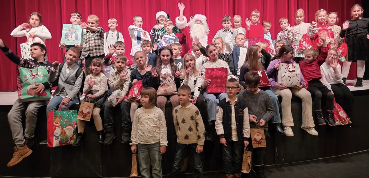 Zdjęcie przedstawia uczniów klas od 1-3, siedzących na scenie w teatrze w towarzystwie św. Mikołaja