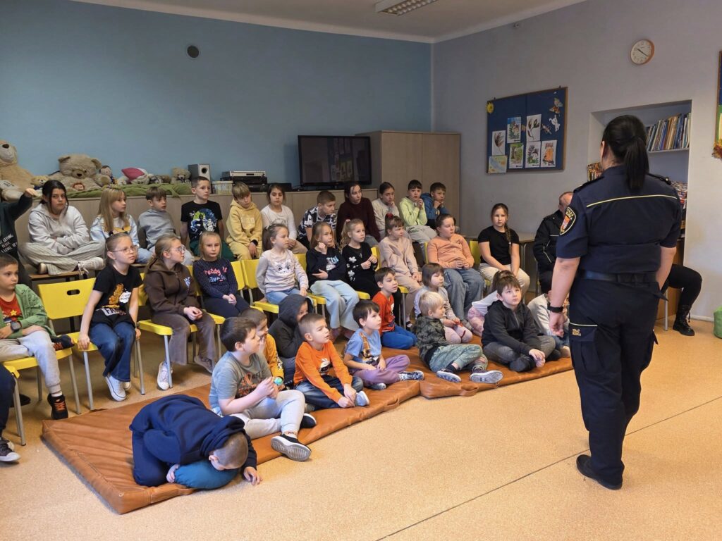 Na zdjęciu przedstawione są dzieci z klas 1-3 które słuchają Pani ze Straży Miejskiej, która prowadzi dla nich zajęcia na temat bezpieczeństwa