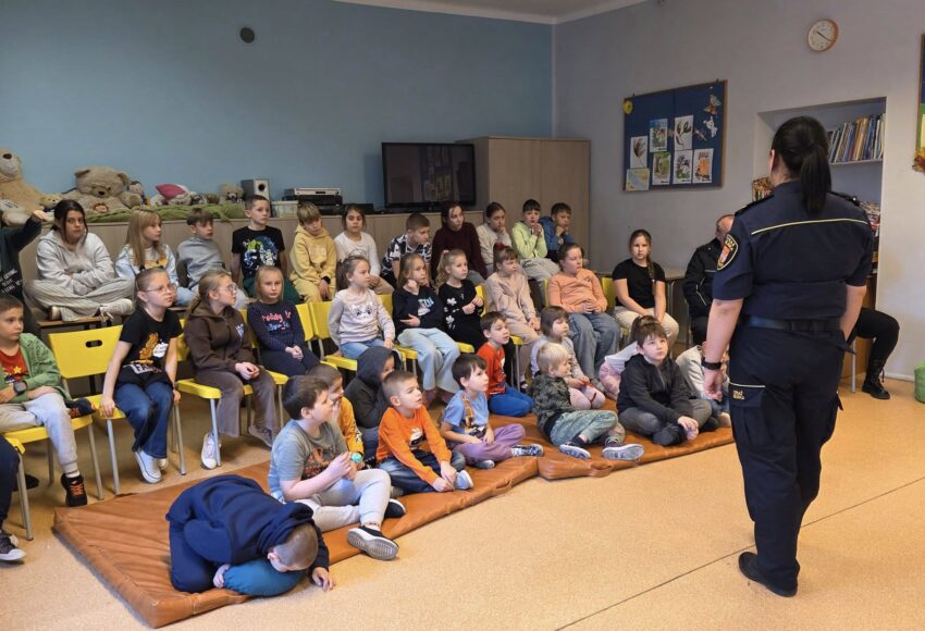 Na zdjęciu przedstawione są dzieci z klas 1-3 które słuchają Pani ze Straży Miejskiej, która prowadzi dla nich zajęcia na temat bezpieczeństwa