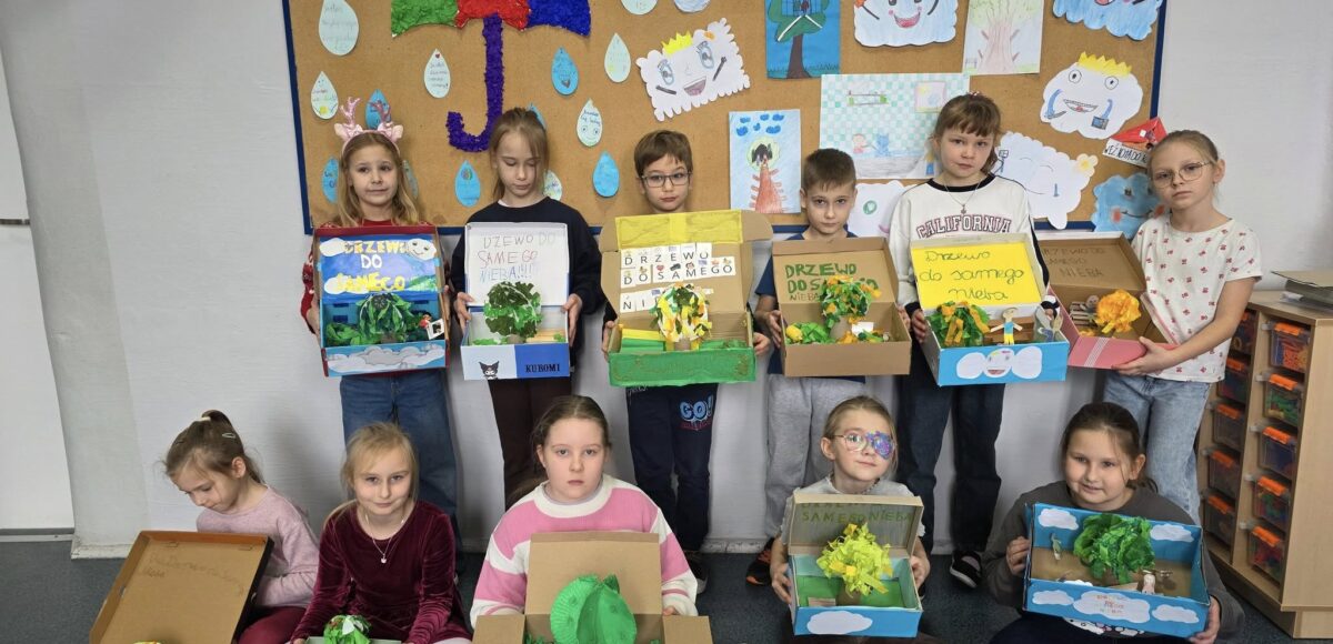 „Uczniowie klasy II prezentują wykonane prace plastyczno-techniczne związane z lekturą »Drzewo do samego nieba« w ramach projektu »Czytam z klasą – Lekturki spod chmurki«.”