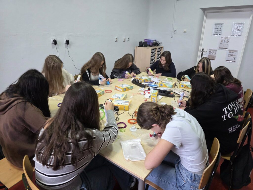 Uczennice klasy ósmej pracujące przy jednym stole podczas lekcji informatyki – tworzą świąteczne ozdoby z użyciem długopisów 3D w ramach programu Laboratoria Przyszłości.