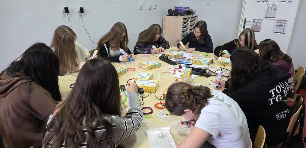 Uczennice klasy ósmej pracujące przy jednym stole podczas lekcji informatyki – tworzą świąteczne ozdoby z użyciem długopisów 3D w ramach programu Laboratoria Przyszłości.