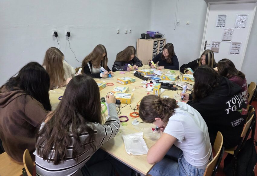 Uczennice klasy ósmej pracujące przy jednym stole podczas lekcji informatyki – tworzą świąteczne ozdoby z użyciem długopisów 3D w ramach programu Laboratoria Przyszłości.