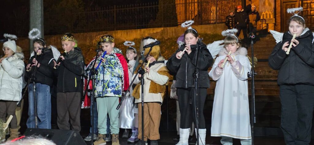Uczniowie Szkoły Podstawowej nr 6 występujący podczas wydarzenia świątecznego. Dzieci przebrane za anioły i kolędników grają na fletach na scenie plenerowej.