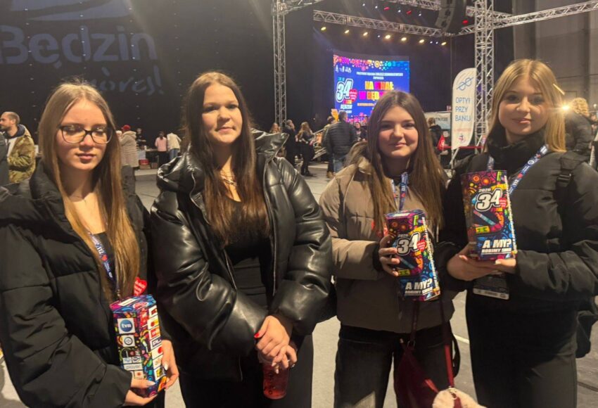 Szkolne wolontariuszki podczas 34. Finału Wielkiej Orkiestry Świątecznej Pomocy w hali Będzin Arena, trzymające puszki WOŚP na tle sceny wydarzenia.