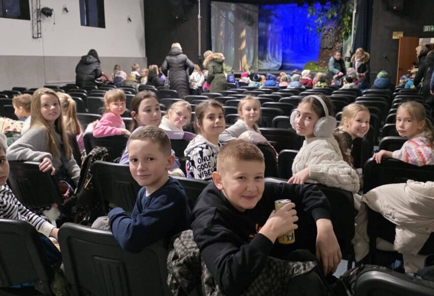 Uczniowie klas I–IV siedzą na widowni w Domu Kultury Grodziec przed rozpoczęciem musicalu »Pinokio«, oczekując na spektakl