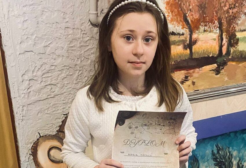 „Uczennica klasy IV, Marysia Machoń, prezentuje dyplom otrzymany za wyróżnienie w Powiatowym Konkursie Aktorskim.”