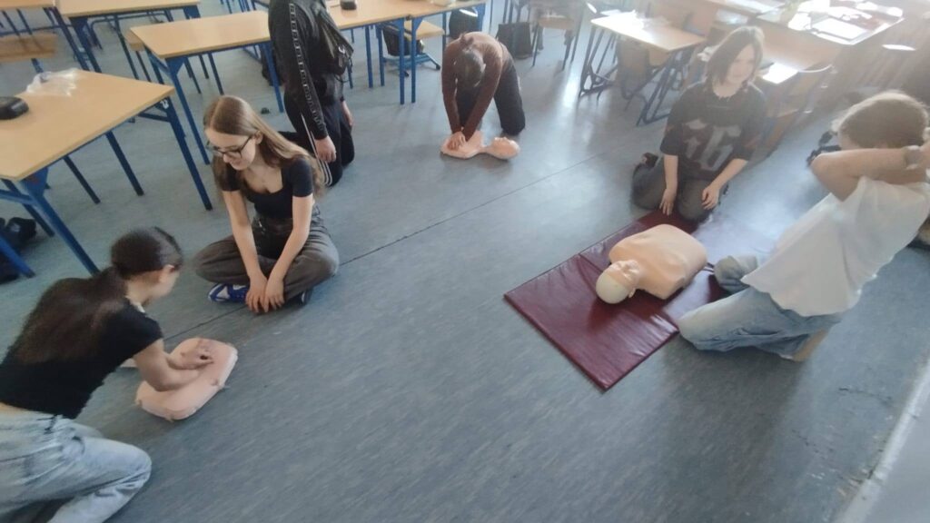 Uczniowie klas 4–8 podczas zajęć projektu EduAkcja ćwiczą masaż serca i resuscytację na fantomach w sali lekcyjnej.