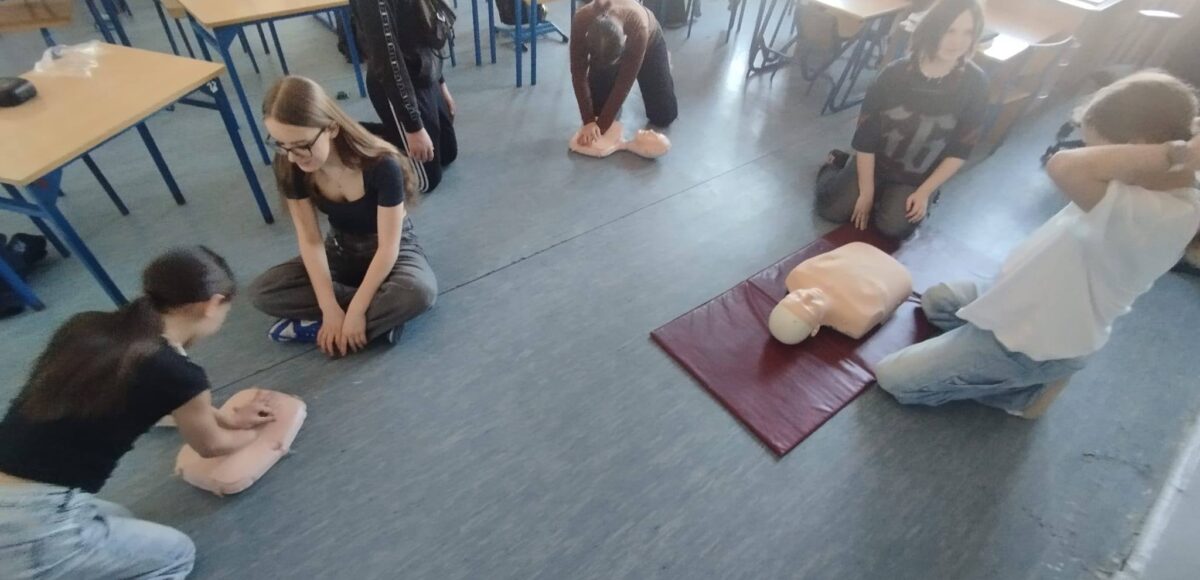 Uczniowie klas 4–8 podczas zajęć projektu EduAkcja ćwiczą masaż serca i resuscytację na fantomach w sali lekcyjnej.