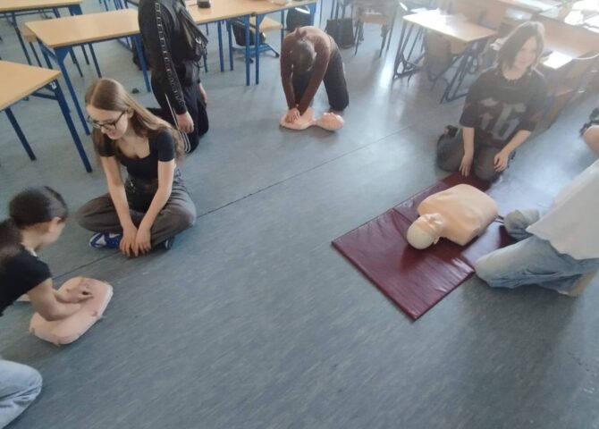 Uczniowie klas 4–8 podczas zajęć projektu EduAkcja ćwiczą masaż serca i resuscytację na fantomach w sali lekcyjnej.