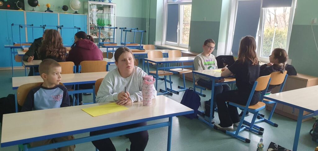 Uczniowie podczas warsztatów integracyjnych pracują w grupach w sali lekcyjnej w ramach programu EduAkcja.