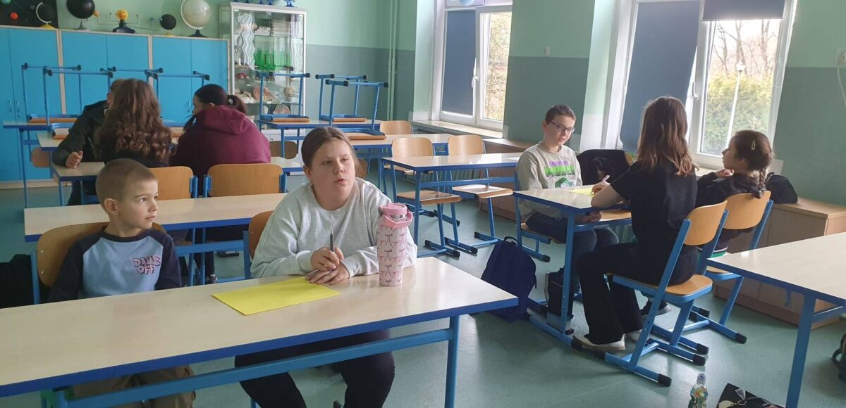 Uczniowie podczas warsztatów integracyjnych pracują w grupach w sali lekcyjnej w ramach programu EduAkcja.