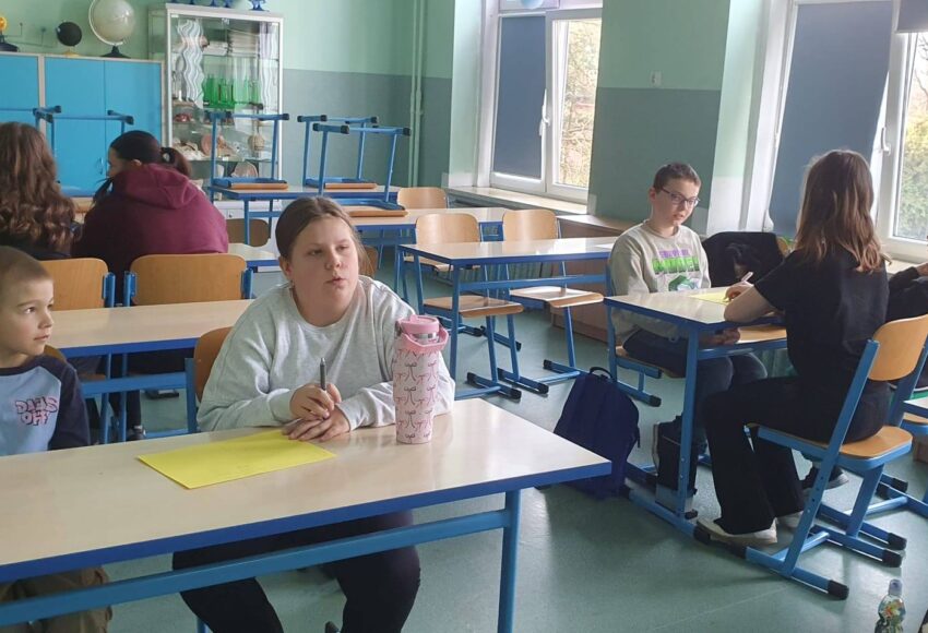 Uczniowie podczas warsztatów integracyjnych pracują w grupach w sali lekcyjnej w ramach programu EduAkcja.