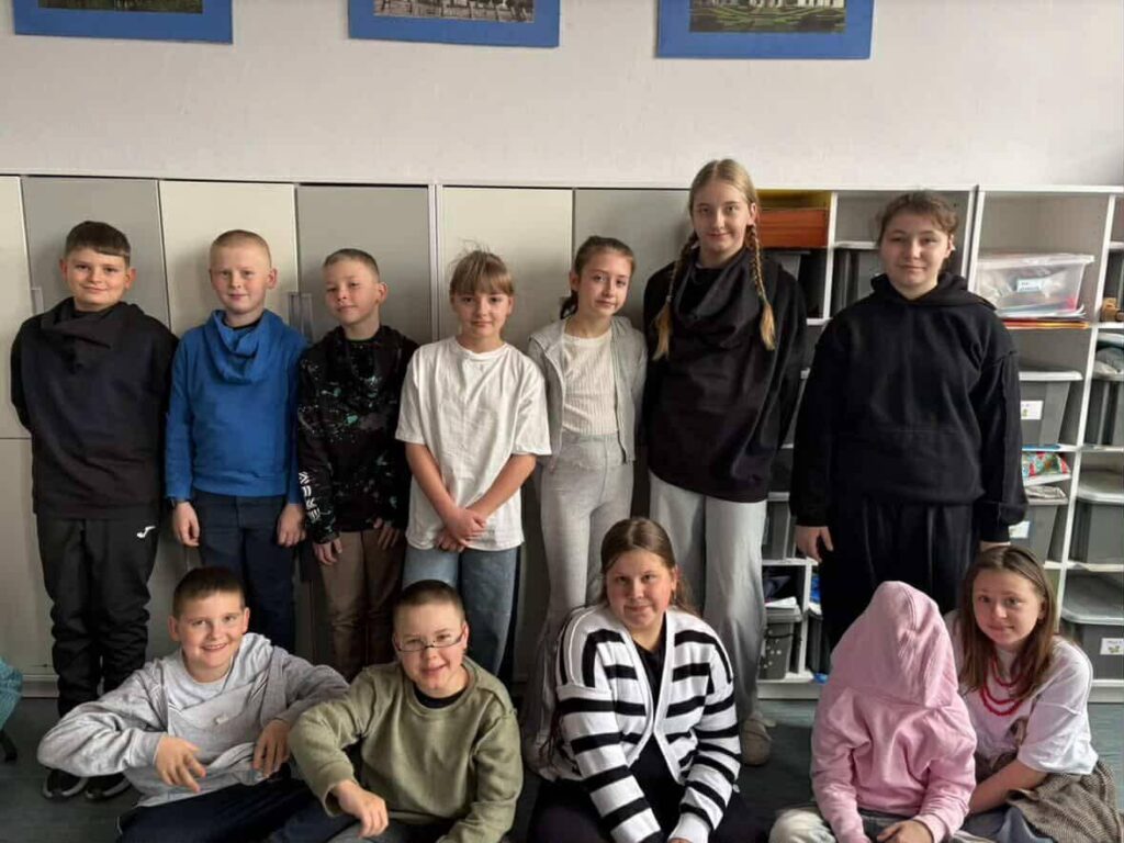 Uczniowie szkoły pozujący wspólnie w klasie podczas Szalonego Wiosennego Tygodnia, prezentujący różnorodne stylizacje związane z jednym z dni tematycznych.