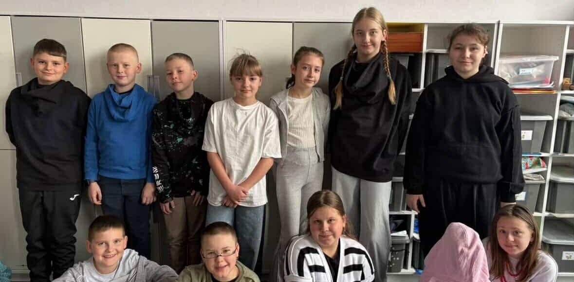 Uczniowie szkoły pozujący wspólnie w klasie podczas Szalonego Wiosennego Tygodnia, prezentujący różnorodne stylizacje związane z jednym z dni tematycznych.