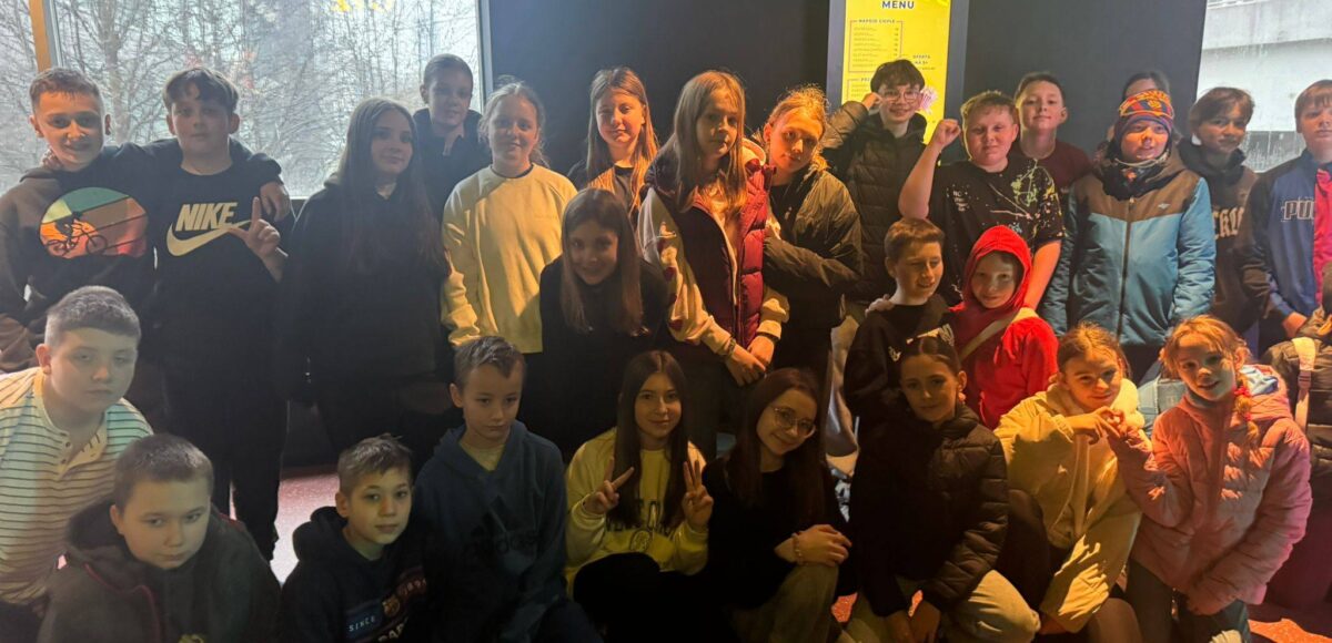 Uczniowie klas 5 i 6 pozują do wspólnego zdjęcia podczas wycieczki do Pixel XL w Katowicach, stojąc w nowoczesnej przestrzeni rozrywkowej