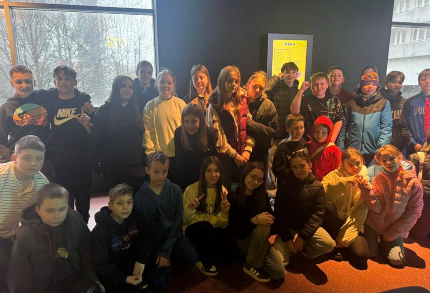 Uczniowie klas 5 i 6 pozują do wspólnego zdjęcia podczas wycieczki do Pixel XL w Katowicach, stojąc w nowoczesnej przestrzeni rozrywkowej