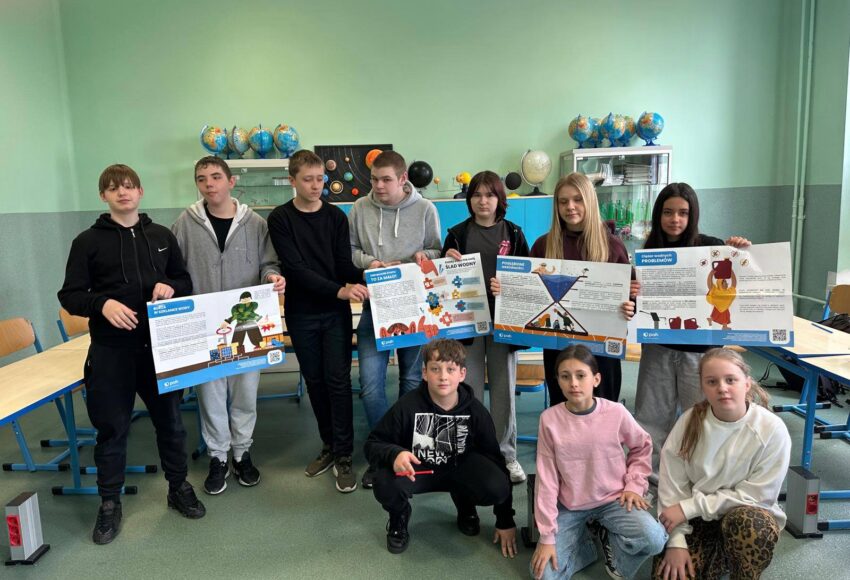 Uczniowie pozują w sali lekcyjnej, prezentując plansze edukacyjne dotyczące oszczędzania wody i globalnych problemów związanych z dostępem do wody w ramach Światowego Dnia Wody.