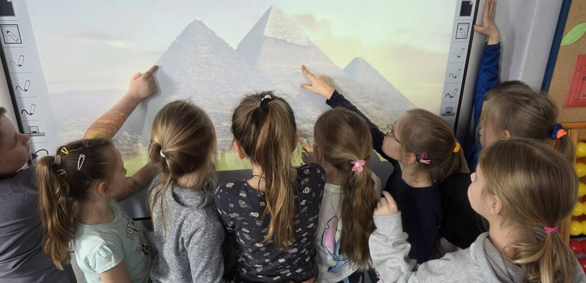 Uczniowie klas 2 podczas zajęć oglądają i wskazują na tablicy multimedialnej piramidy w Gizie, poznając sztukę i architekturę starożytnego Egiptu.