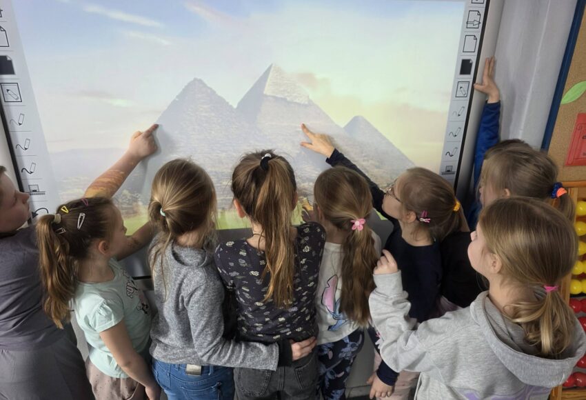 Uczniowie klas 2 podczas zajęć oglądają i wskazują na tablicy multimedialnej piramidy w Gizie, poznając sztukę i architekturę starożytnego Egiptu.