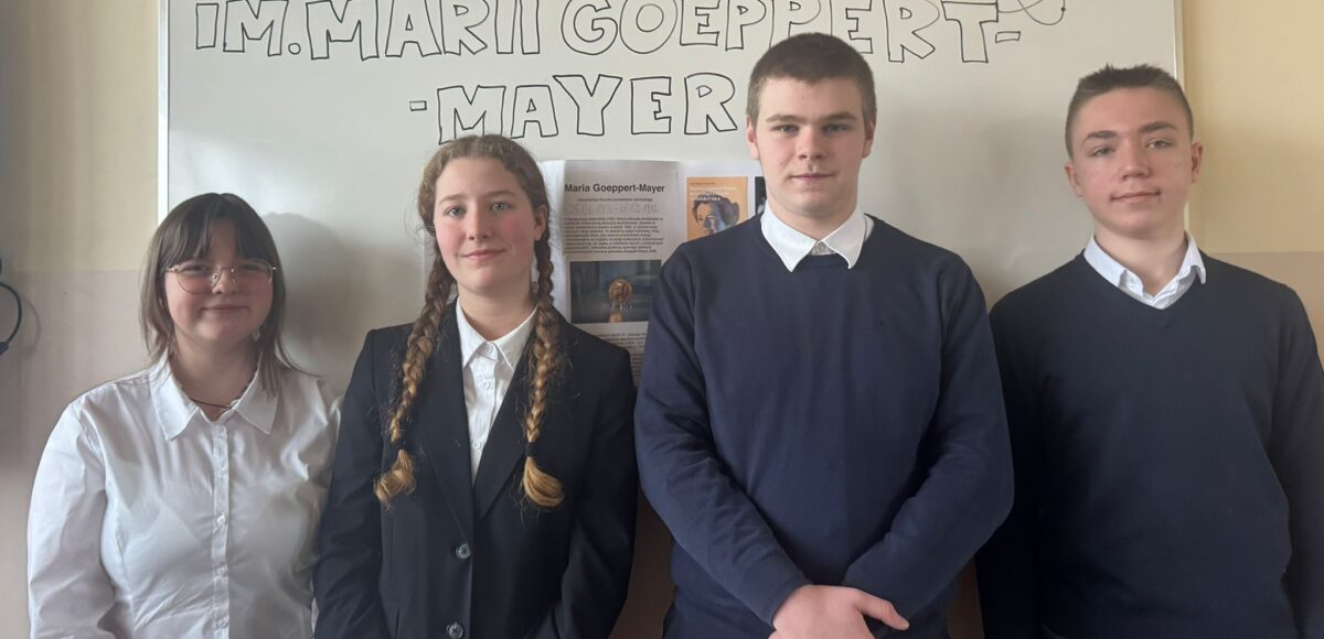Uczniowie szkoły pozujący na tle tablicy z napisem „XIV Konkurs im. Marii Goeppert-Mayer”, reprezentujący szkołę w konkursie interdyscyplinarnym w języku angielskim.