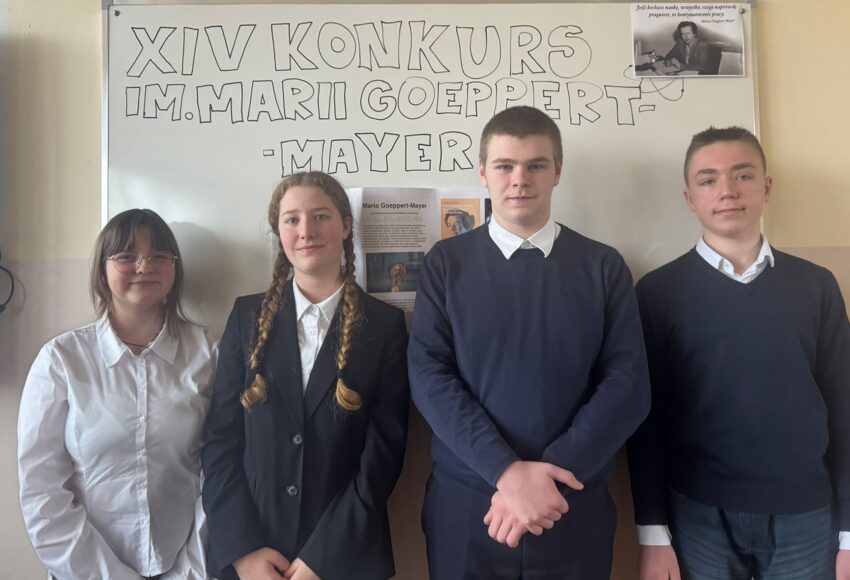 Uczniowie szkoły pozujący na tle tablicy z napisem „XIV Konkurs im. Marii Goeppert-Mayer”, reprezentujący szkołę w konkursie interdyscyplinarnym w języku angielskim.