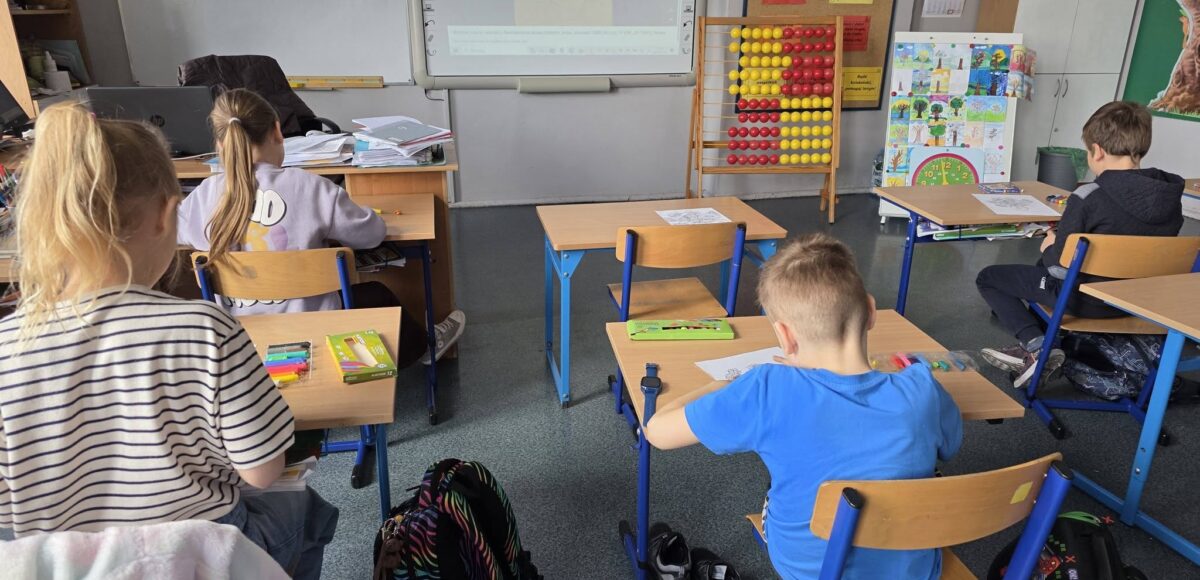 Uczniowie podczas zajęć plastycznych w klasie, pracują przy ławkach, inspirując się twórczością Vincenta van Gogha wyświetlaną na tablicy interaktywnej.