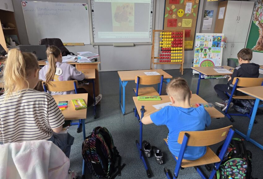 Uczniowie podczas zajęć plastycznych w klasie, pracują przy ławkach, inspirując się twórczością Vincenta van Gogha wyświetlaną na tablicy interaktywnej.
