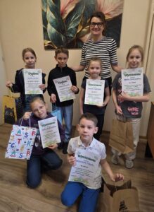 Uczniowie wraz z Dyrekcją szkoły prezentują dyplomy i nagrody otrzymane w konkursie plastycznym „Wielkanocna Pisanka”.