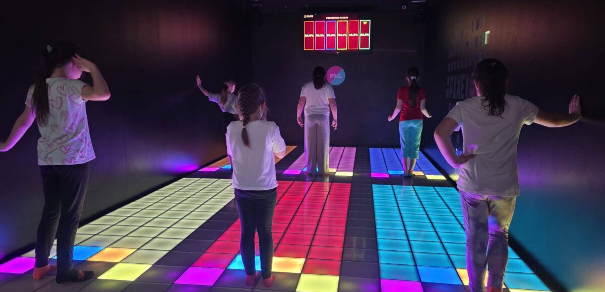 Uczniowie podczas zabawy na interaktywnej, podświetlanej podłodze w Pixel XL, biorą udział w grze ruchowej.