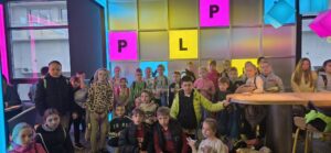 Uczniowie klas I–III podczas wycieczki do Pixel XL w Katowicach, pozują na tle kolorowej, interaktywnej przestrzeni.
