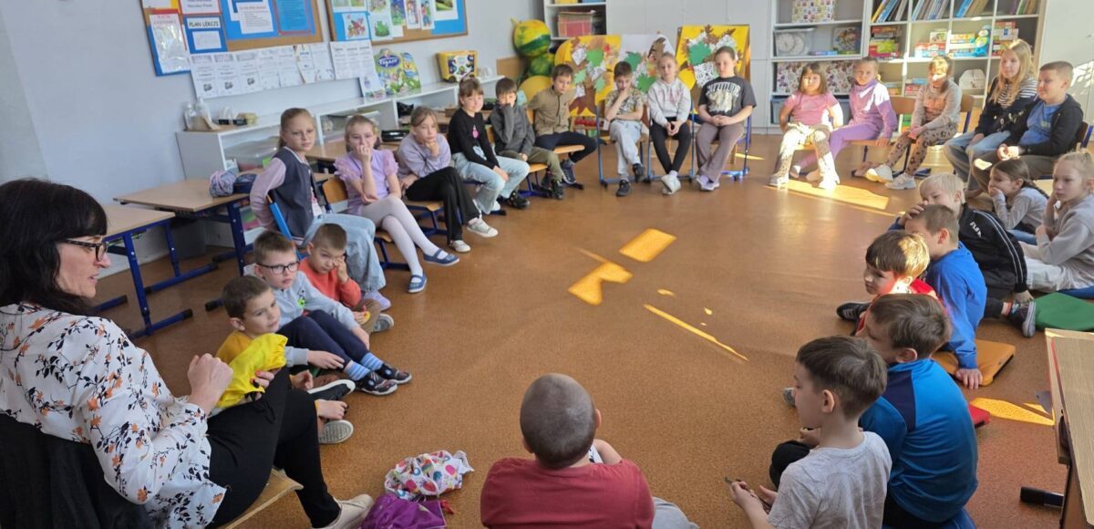 Uczniowie klas 1–2 siedzą w kręgu w sali lekcyjnej i uczestniczą w zajęciach profilaktycznych programu „Cukierki”, prowadzonych przez nauczyciela.