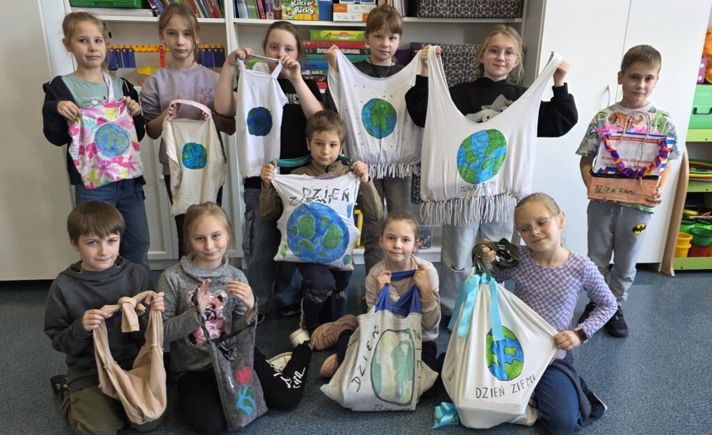 Uczniowie klasy 2 prezentują torby ekologiczne wykonane z materiałów z recyklingu z okazji Dnia Ziemi.