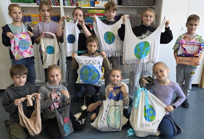 Uczniowie klasy 2 prezentują torby ekologiczne wykonane z materiałów z recyklingu z okazji Dnia Ziemi.