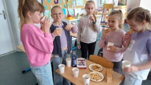 Uczennice podczas zajęć z okazji Dnia Języka Angielskiego próbują brytyjskiej herbaty i ciasteczek w klasie.
