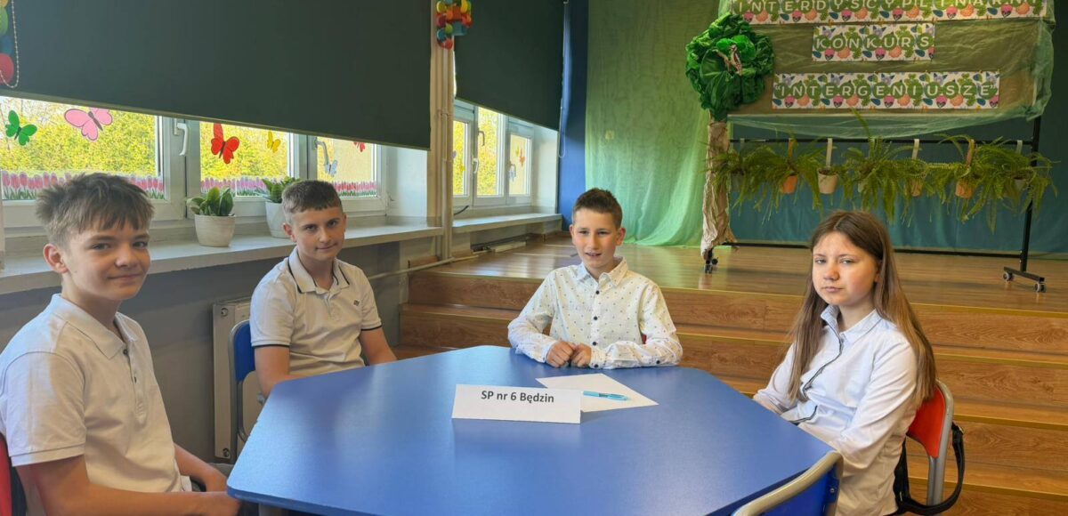 Uczniowie naszej szkoły podczas Powiatowego Konkursu Interdyscyplinarnego „InterGeniusze”, siedzą przy stoliku konkursowym.