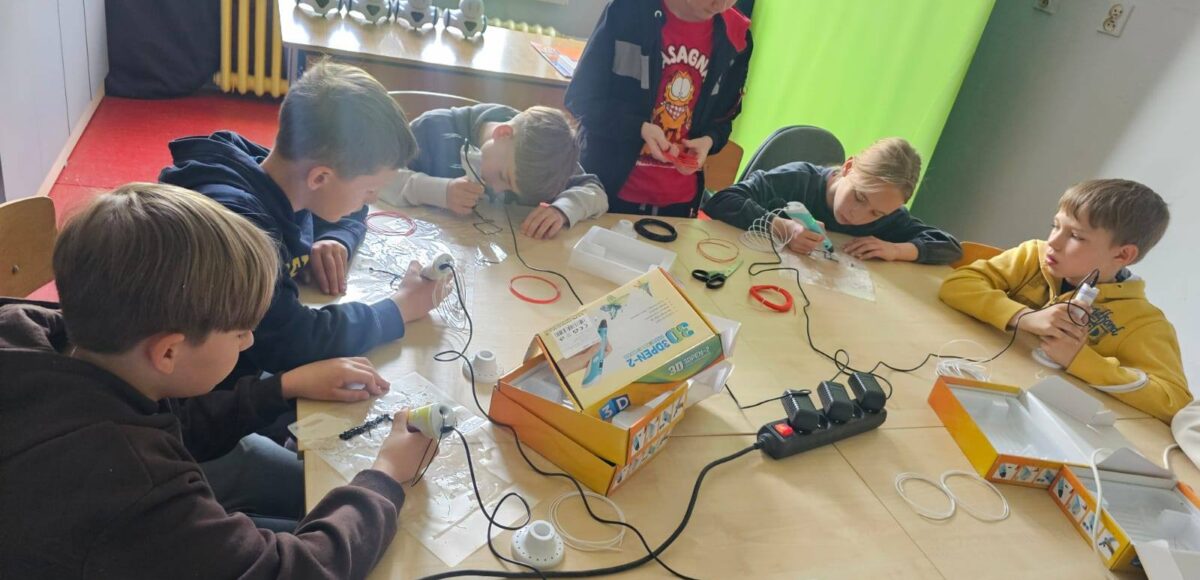 Uczniowie klasy III podczas zajęć w Laboratorium Przyszłości pracują z długopisami 3D przy wspólnym stole.