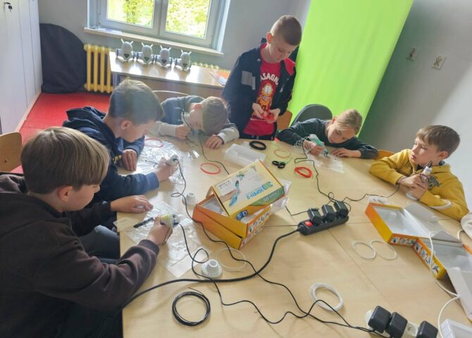 Uczniowie klasy III podczas zajęć w Laboratorium Przyszłości pracują z długopisami 3D przy wspólnym stole.