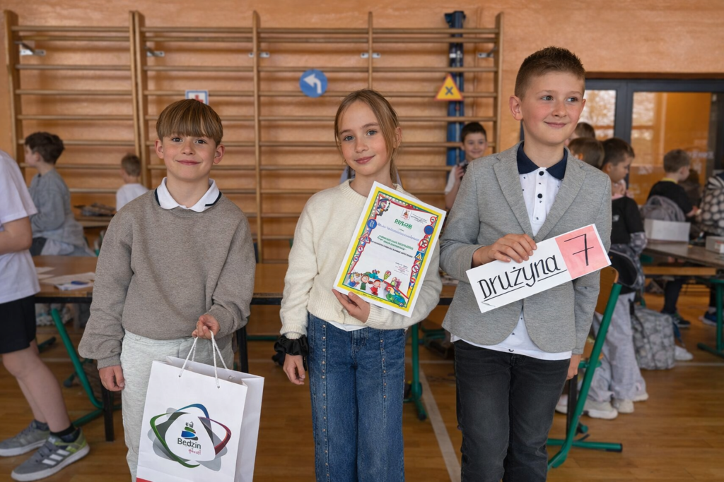 Uczniowie klasy trzeciej prezentują dyplom i oznaczenie drużyny podczas międzyszkolnego turnieju bezpieczeństwa.