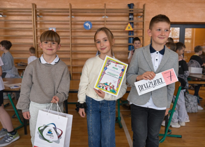 Uczniowie klasy trzeciej prezentują dyplom i oznaczenie drużyny podczas międzyszkolnego turnieju bezpieczeństwa.