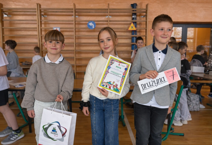 Uczniowie klasy trzeciej prezentują dyplom i oznaczenie drużyny podczas międzyszkolnego turnieju bezpieczeństwa.