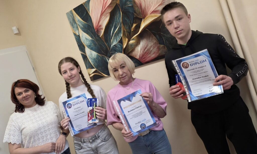 Uczniowie wraz z nauczycielami prezentują dyplomy i nagrody zdobyte w ogólnopolskim konkursie matematyczno-informatycznym InstaLogik.