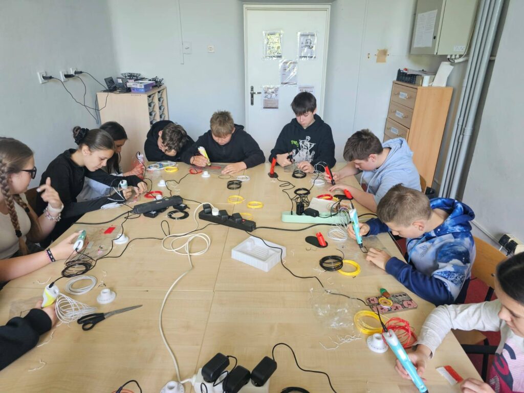 Uczniowie klas V–VI podczas zajęć w Laboratorium Przyszłości pracują z długopisami 3D