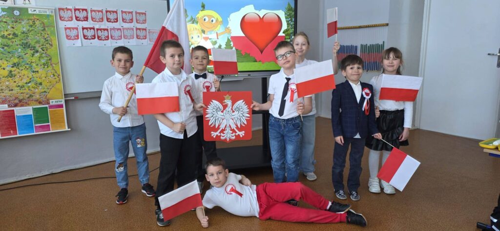 Uczniowie klasy pierwszej z flagami Polski podczas zajęć patriotycznych z okazji świąt majowych