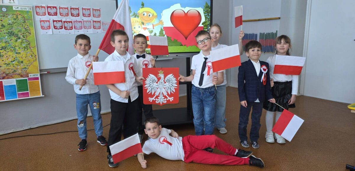 Uczniowie klasy pierwszej z flagami Polski podczas zajęć patriotycznych z okazji świąt majowych