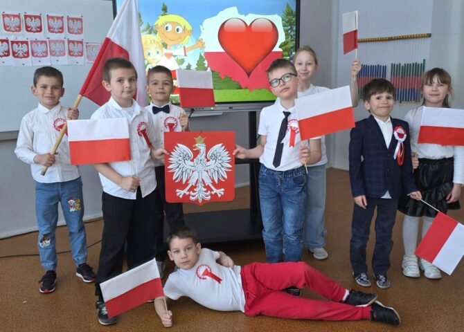 Uczniowie klasy pierwszej z flagami Polski podczas zajęć patriotycznych z okazji świąt majowych