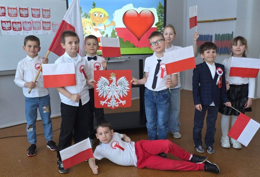 Uczniowie klasy pierwszej z flagami Polski podczas zajęć patriotycznych z okazji świąt majowych